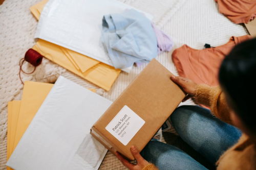 A person holding a brown mailer box