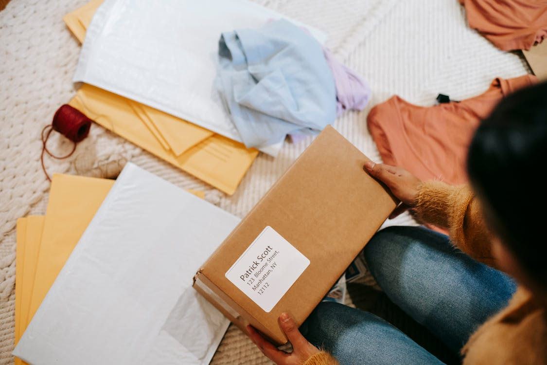 A person holding a brown mailer box